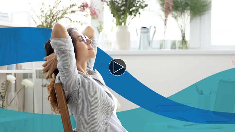 picture of woman at table with computer taking a break to stretch