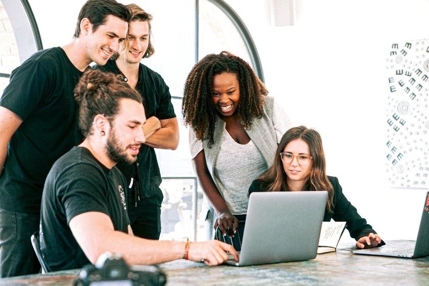 picture of five people in looking at a laptop on a table