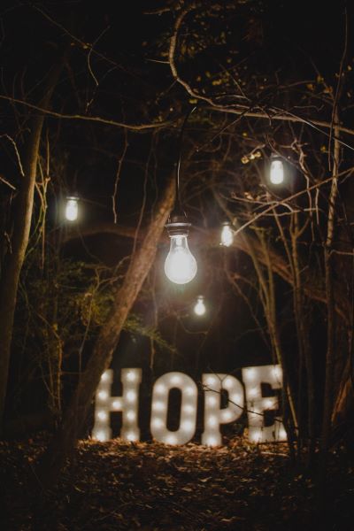picture of night scene in the woods with an illuminated sign that says "Hope"