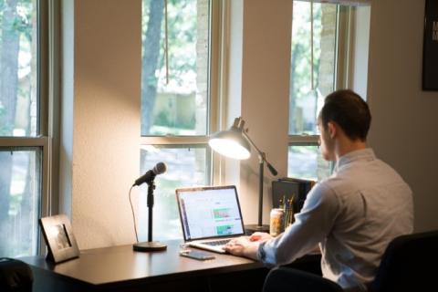picture of person on laptop with lamp next to them