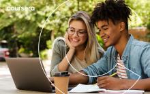 picture of two people in front of a laptop smiling 