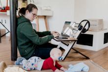 image of woman working on laptop with infant on floor beside her