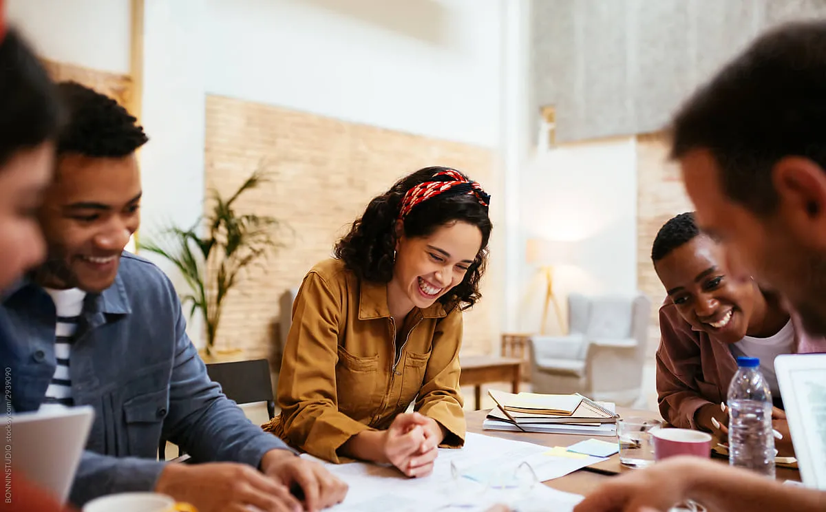 picture of employees collaborating around a table smiling.