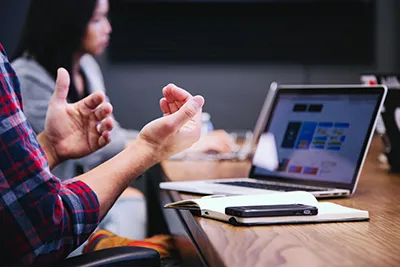 picture of person talking with hands in front of a laptop computer 